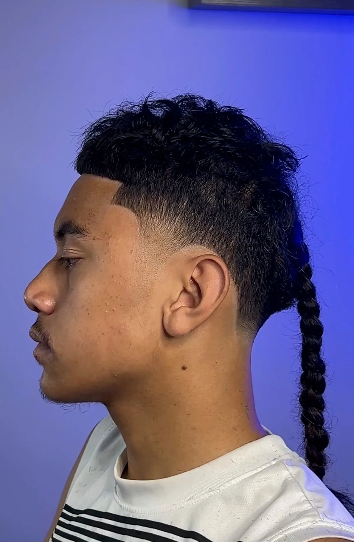 Textured top over a burst fade, with the back length braided into a single tail.
