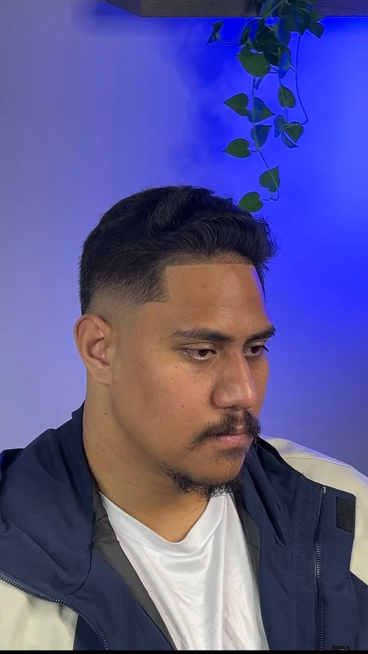 Side-swept pompadour over a mid skin fade, with the hairline edged square at the temple.