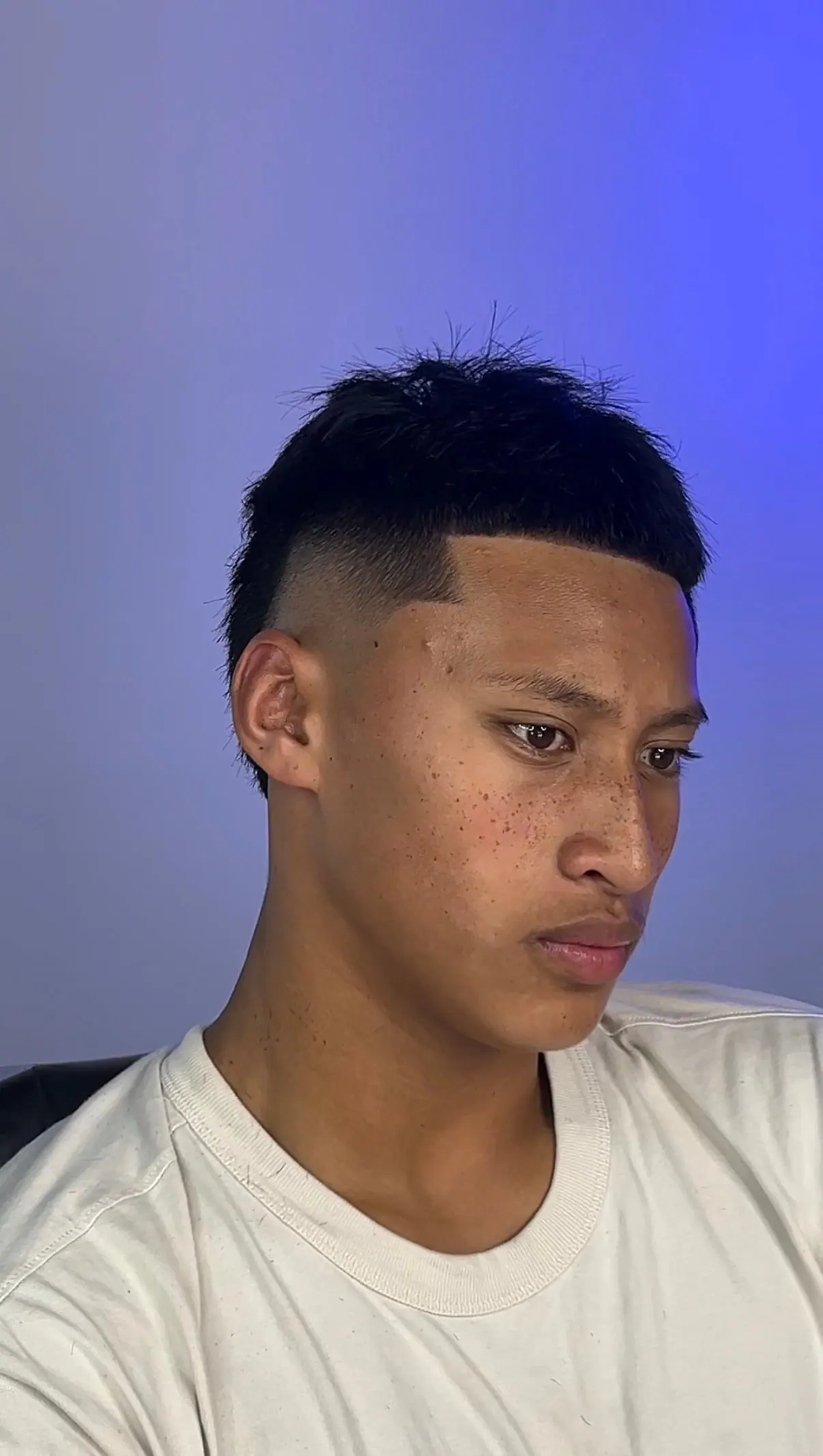 Straight fringe cut level across the forehead, over a mid skin fade.